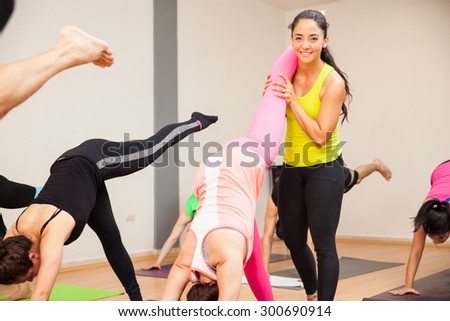 Portrait of a beautiful Hispanic yoga instructor helping students with their poses
