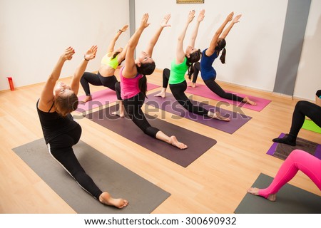 Young women and instructor working out together in their yoga class at a gym