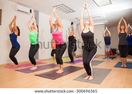 Wide angle view of a big group of people doing a chair pose during a real yoga class