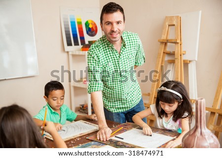Portrait of a young art teacher helping his students and smiling in the classroom