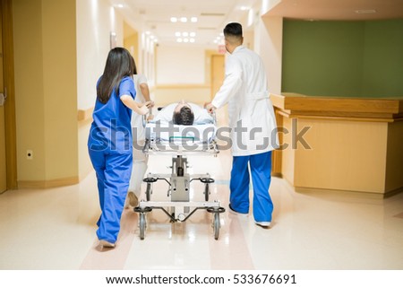 Similar – Image, Stock Photo Group of doctors transporting patient to operating room