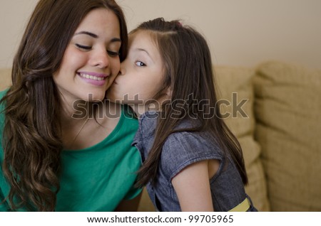 Daughter kissing her mother on the cheek in the living room