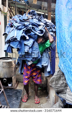 Mumbai, India - February 25, 2015: a boy was carrying jeans in Dhobi Ghat Laundry District, a well know open air laundromat in downtown, Mumbai, Maharashtra State, India.