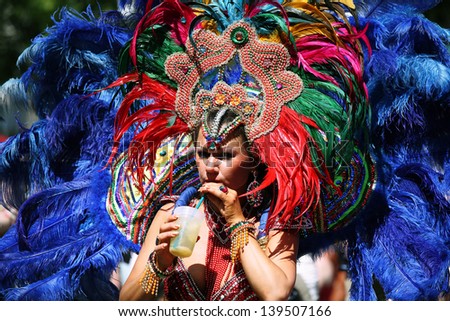 BERLIN - MAY 19: Unidentified woman dancer dressed in multicolored feather carnival costume drinks a cocktail at the annual Berlin Carnival of Cultures on May 19, 2013 in Berlin.