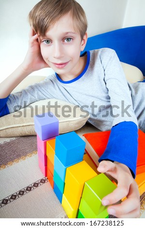 Cute happy little child lying on a sofa playing with colorful toys smiling