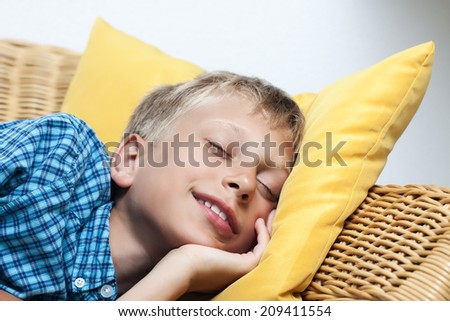 Beautiful little boy sleeping peacefully on a wicker sofa