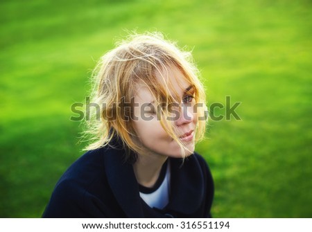 Lovely young woman sitting in summer field dreaming with a melancholy expression. Sadness and love concept. (soft focus, filtered)