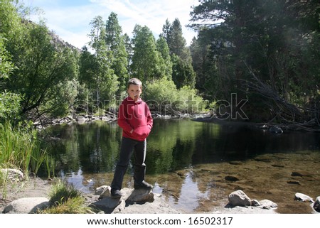 Young boy enjoying nature next to a stream in the High Sierras California