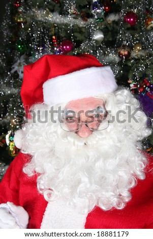 Santa clause sitting in front of a Christmas tree