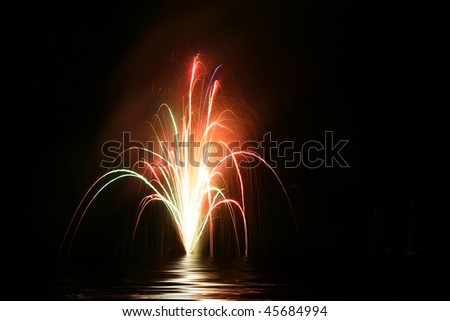 Fireworks reflected over the dark lake water