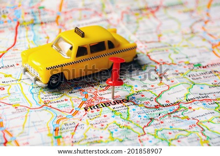 Red push pin pointing at Freiburg,Germany  map   and a taxi