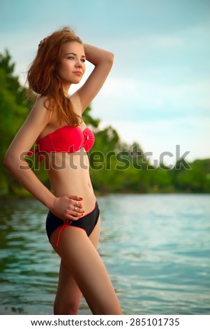beautiful young blond woman in a swimsuit on the beach resting enjoying the evening sun and good weather