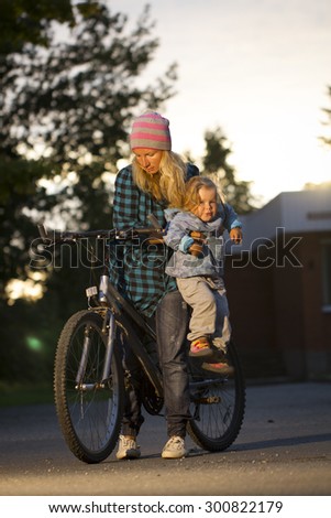 mother and daughter on a bicycle . girl playing the mother climbed on a bicycle . summer rest