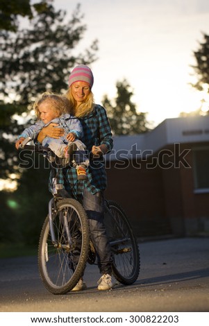 mother and daughter on a bicycle . girl playing the mother climbed on a bicycle . summer rest