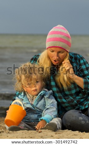 Mother and daughter sitting at the sea . early autumn , end of summer . Family vacation by the sea