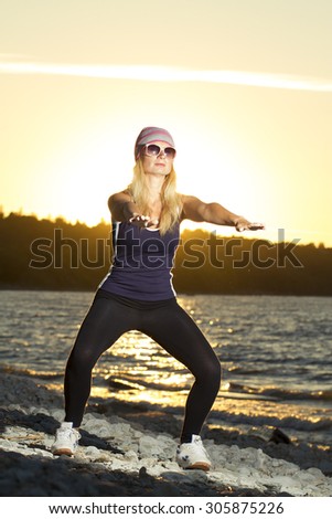 Fitness sport model doing exercises during outdoor work out on sunrise. Beautiful caucasian female training outside on seaside in the morning