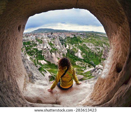 Woman looking into the distance against the background of incredible landscape with  mountains , geological structures in Goreme, Cappadocia,  Turkey