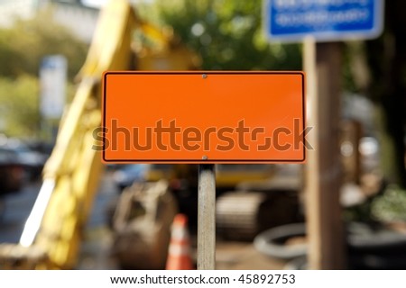 A blank orange construction sign against construction site