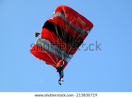 Red  white and black sail parachute on blue sky
