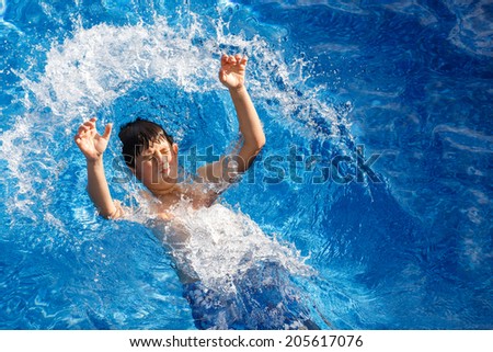 Boy jumping in the home garden swimming pool with clear water