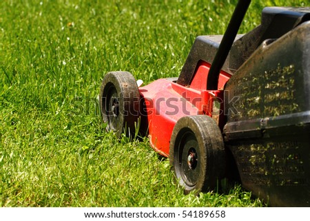 Detail of lawnmower on green grass in sunny day