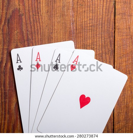Four aces vintage poker game playing cards on a weathered wood table in an old western frontier gambling establishment saloon.