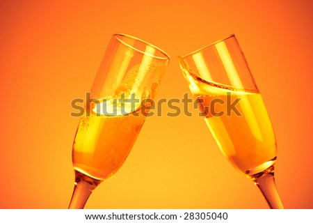 Pair of champagne flutes on orange background