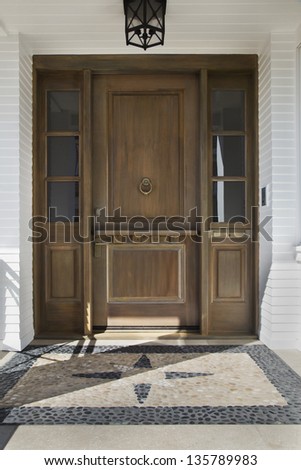 Front door of an upscale home/Vertical shot of a wooden front door of an upscale home with view of decorative time and windows with a reflection