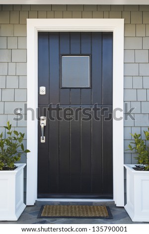 Front door of an upscale home/Vertical shot of a black front door of an upscale home with view of sky, plants and roof line.