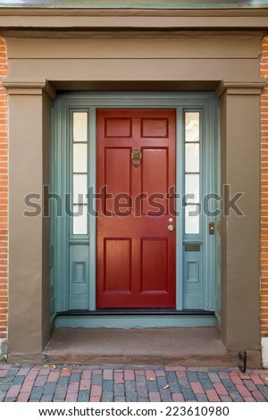 Red Front Door with Blue Door Frame and Windows on Tan Building on Brick Street