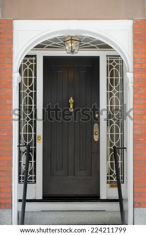 Black Paneled Front Door with Ornate Framing Windows under White Arch