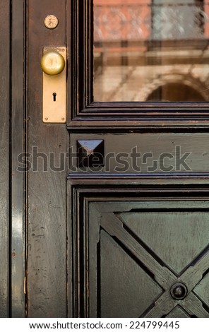Close-up of Black Front Door with Crosshatch Detail and Gold Doorknob