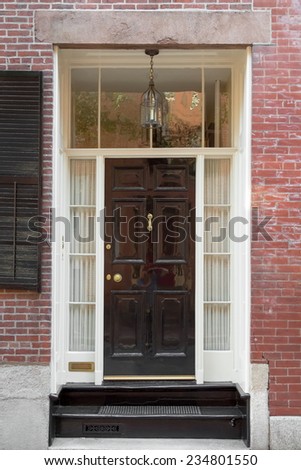 Black Front Door with Tall Surrounding Windows and Hanging Lamp in Brick Building