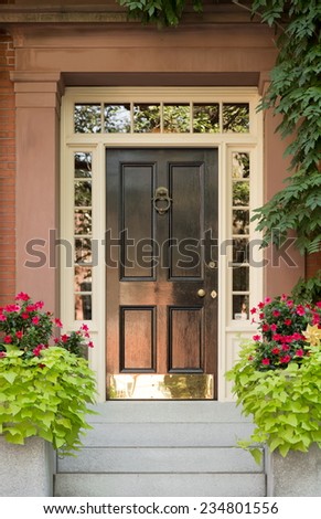 Close Up of Black Door with Surrounding White Door Frame and Windows and Ivy and Potted Plants