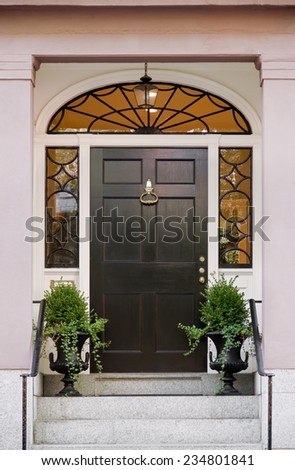 Wide Black Front Door with Surrounding Windows and Lunette and Potted Plants