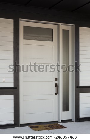 Vertical Angled Shot of White And Black Front Entryway with White Siding, a White Front Door, and Black Framing