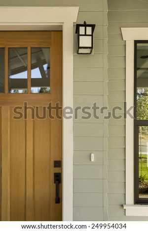 Detail Shot of Natural Wood Front Door with Surrounding White Door Frame, Porch Light, and Side Window