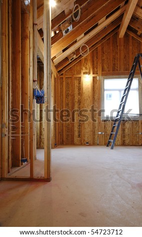 An interior view of a new home under construction with exposed wiring and and a ladder in place. Vertical shot.