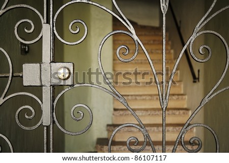 Set of stairs of a residence, blocked by an elegant metal gate. Vertical shot.