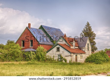 DETROIT, USA - JUNE 9, 2015: An abandoned house with broken windows located next to an empty lot full of weeds  symbolizes urban decay in post-industrial Detroit.