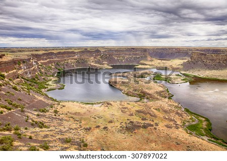 Dray Falls Park in Eastern Washington shows the edge of a dry waterfall over steep cliffs into a deep valley with a lake.