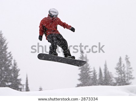 A snowboarder with a red coat getting big air in a jump. It was snowing heavily and the snowflakes are motion-blurred as I panned with the boarder.