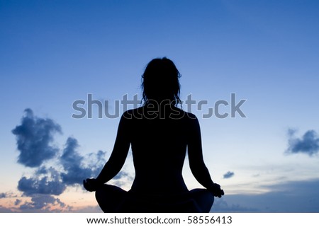 Silhouette of a meditating woman during twilight