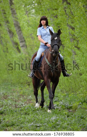 Caucasian woman riding horse for recreation  in the spring woods