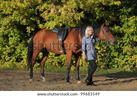Beautiful blond woman leading horse