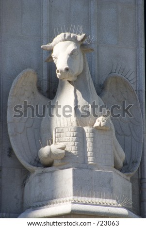 An architectural statue on the side of an old church depicts a well-read cow.