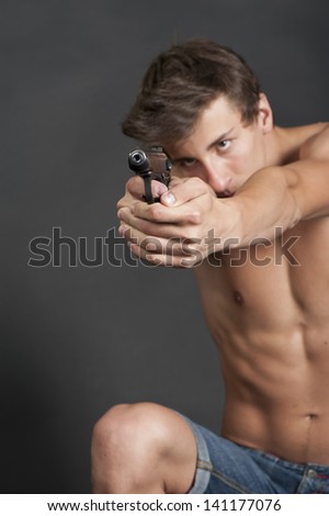 Young guy with a gun in the Studio on a black background