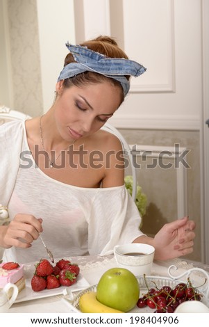 Yung woman in white blouse at a table drinking coffee and cake and fruit