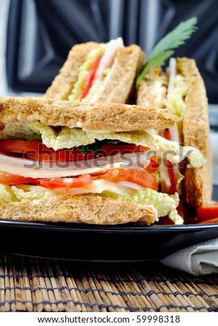 closeup fresh and delicious classic club sandwich over a black glass dish with coffee and toasters