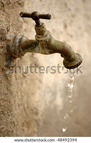 Old tap dripping on a blurred background. reduced depth of field, focus on the dripping water